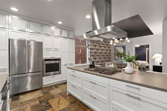 kitchen with white cabinets, ventilation hood, stainless steel appliances, and hanging light fixtures