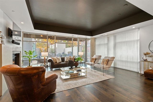 living room with a raised ceiling, hardwood / wood-style floors, and a high end fireplace