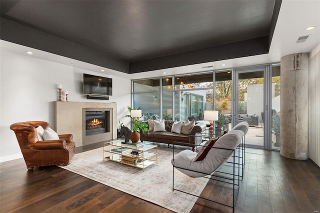 living room with a raised ceiling and dark hardwood / wood-style flooring