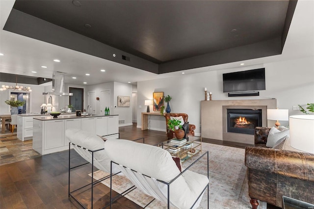 living room with dark wood-type flooring and a tray ceiling