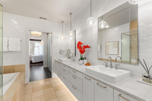 bathroom featuring tiled bath, vanity, and tile walls