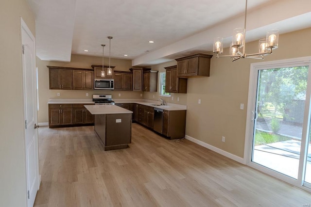 kitchen featuring stainless steel appliances, a kitchen island, pendant lighting, sink, and light hardwood / wood-style floors