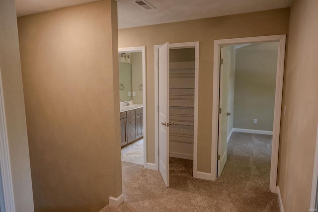 hall featuring light colored carpet and sink