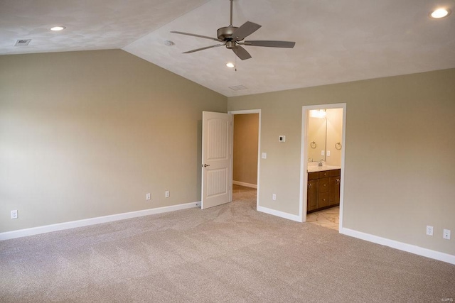 unfurnished bedroom with ceiling fan, connected bathroom, light carpet, and lofted ceiling