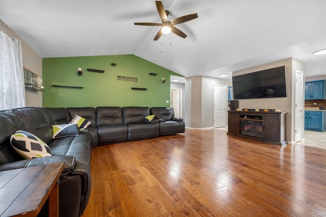 living room with light hardwood / wood-style floors, ceiling fan, and vaulted ceiling