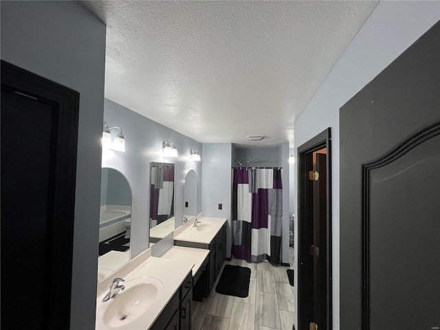 bathroom with a textured ceiling, a shower with shower curtain, and vanity