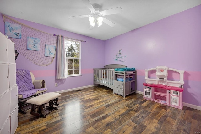 bedroom featuring a crib, ceiling fan, and dark hardwood / wood-style floors