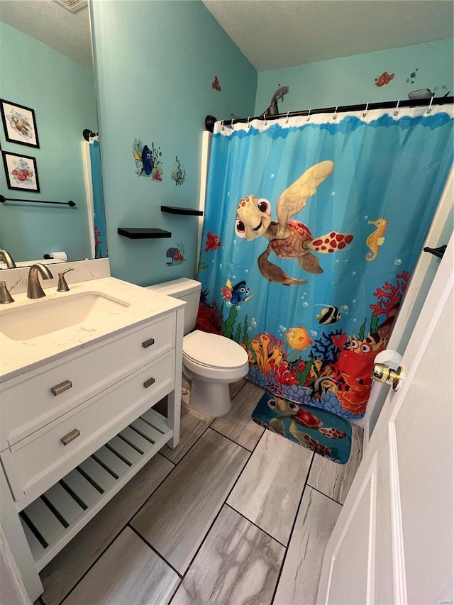 bathroom with toilet, a shower with shower curtain, vanity, and a textured ceiling