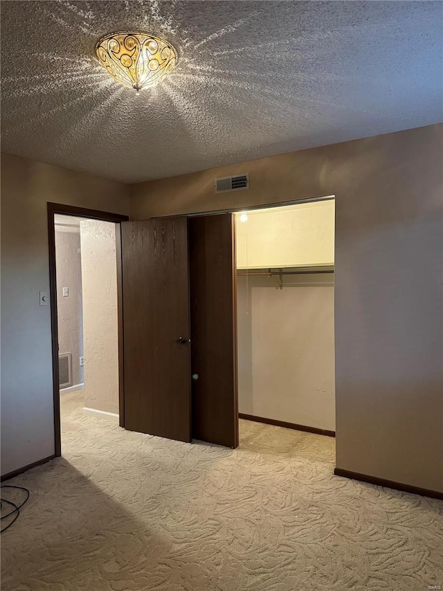 unfurnished bedroom with a closet, a textured ceiling, and light colored carpet