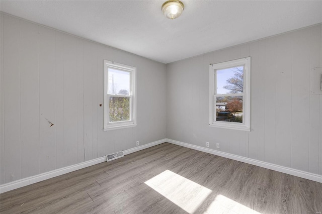 empty room with light hardwood / wood-style flooring and wooden walls