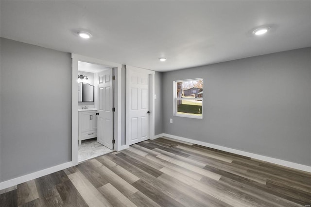 unfurnished bedroom featuring wood-type flooring, connected bathroom, and sink