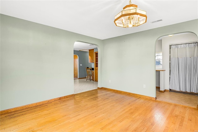 spare room with hardwood / wood-style floors and a chandelier