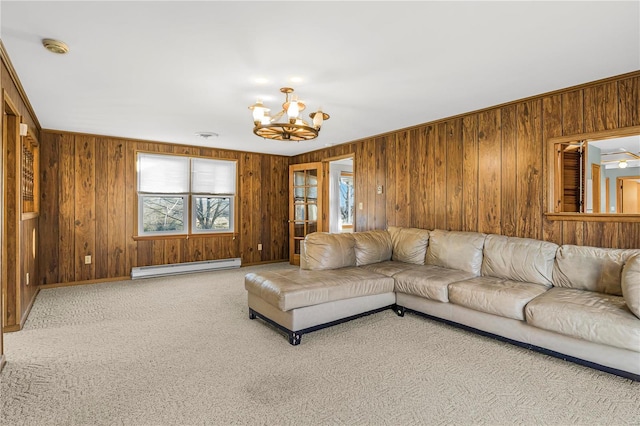 unfurnished living room featuring carpet, an inviting chandelier, a baseboard heating unit, and wood walls