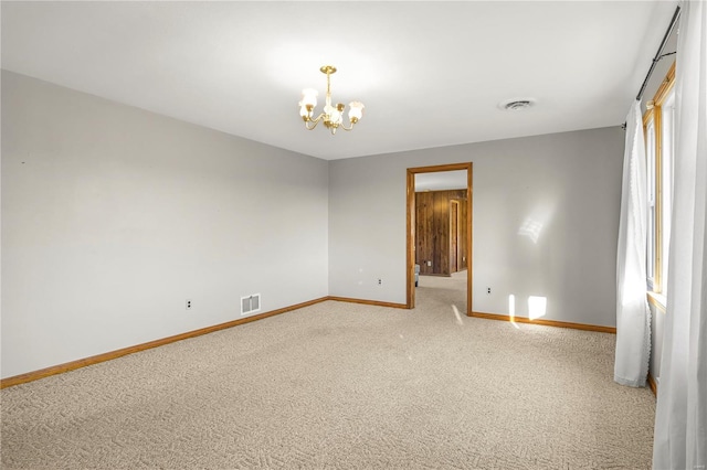 carpeted empty room with a notable chandelier