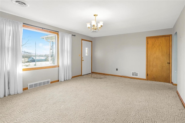 carpeted spare room with a notable chandelier