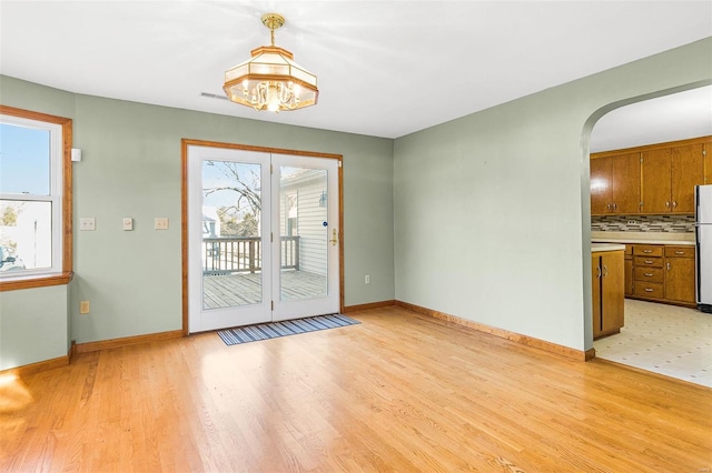 doorway to outside featuring light wood-type flooring and a notable chandelier