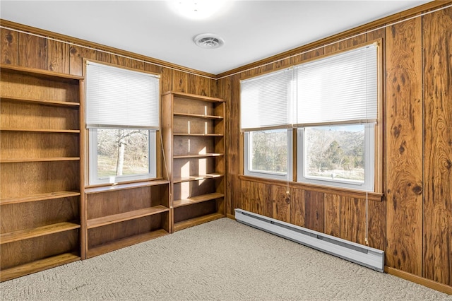 interior space with carpet flooring, baseboard heating, and wood walls