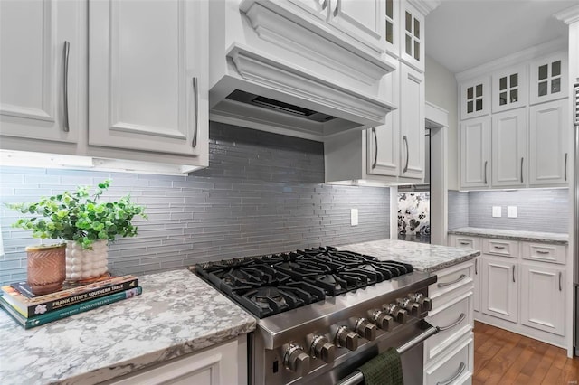 kitchen with white cabinetry, stainless steel range, dark wood-type flooring, decorative backsplash, and custom range hood