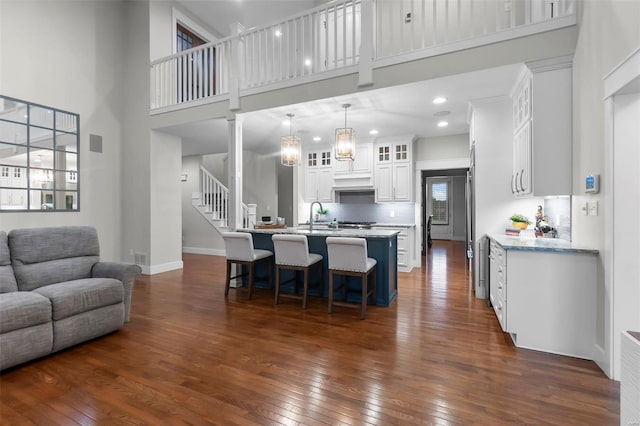 kitchen featuring white cabinetry, dark wood-type flooring, a high ceiling, and decorative light fixtures