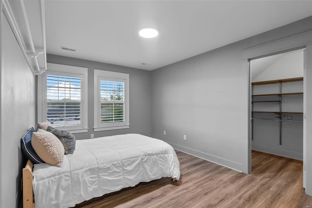 bedroom with a spacious closet and hardwood / wood-style flooring