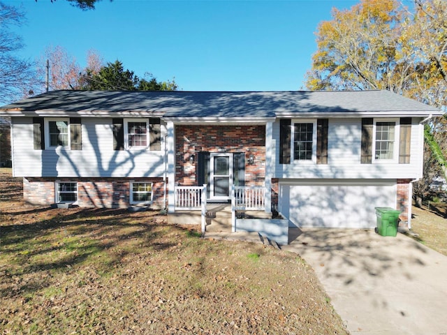 raised ranch featuring a garage and a front lawn