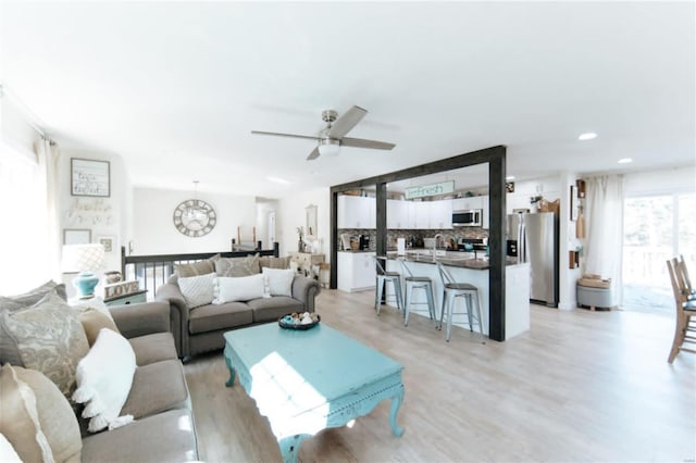 living room featuring light hardwood / wood-style flooring and ceiling fan