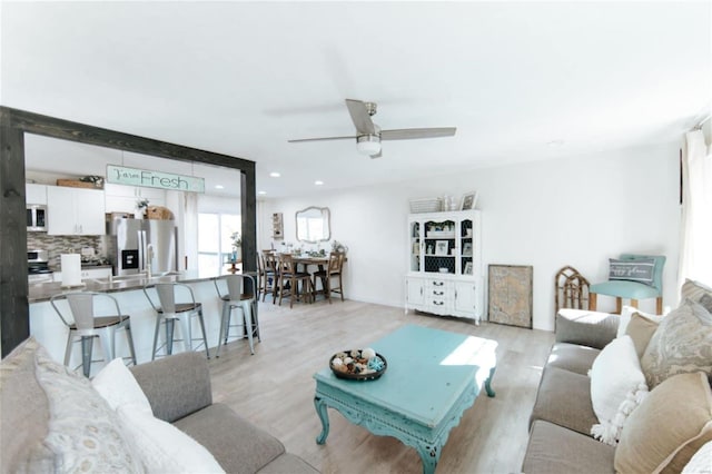 living room featuring ceiling fan and light hardwood / wood-style flooring