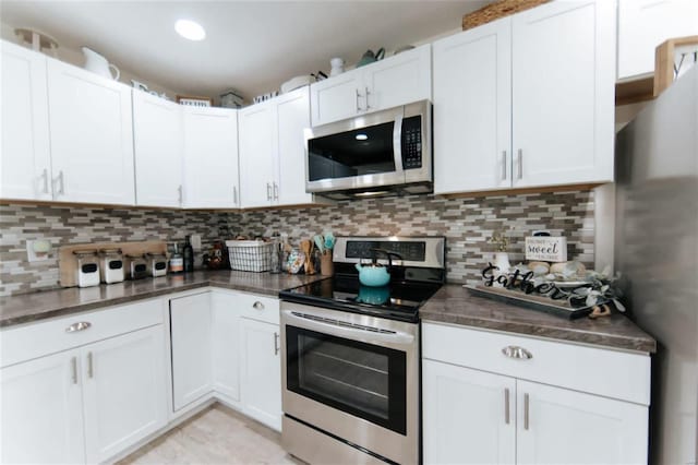 kitchen with decorative backsplash, stainless steel appliances, and white cabinetry