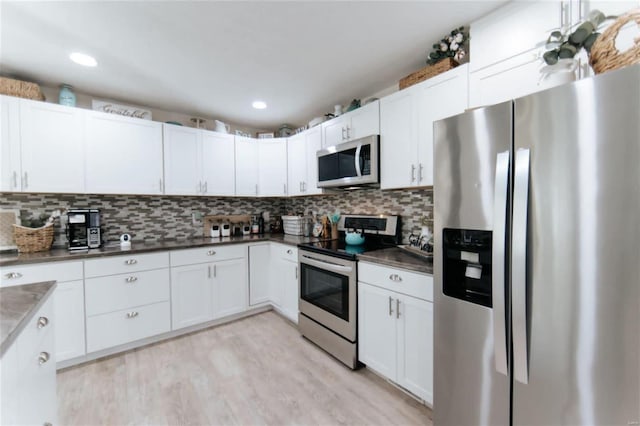 kitchen featuring light wood-type flooring, stainless steel appliances, white cabinetry, and backsplash