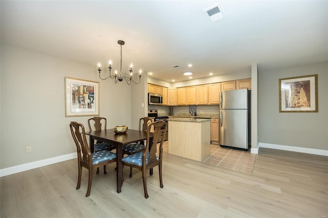 dining area with light wood-type flooring and an inviting chandelier