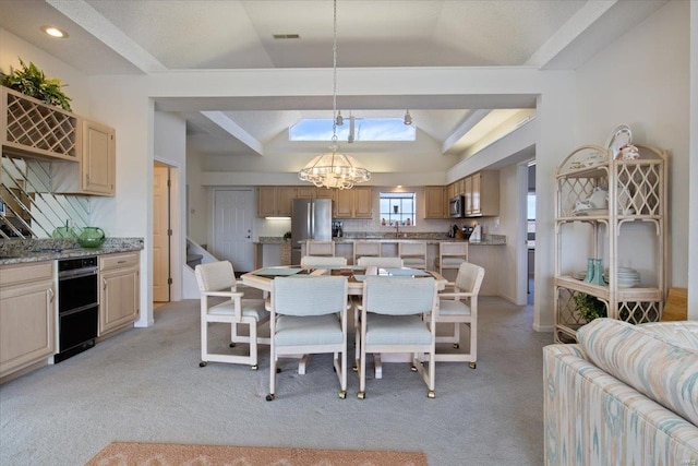 dining area with sink, light colored carpet, a chandelier, and lofted ceiling