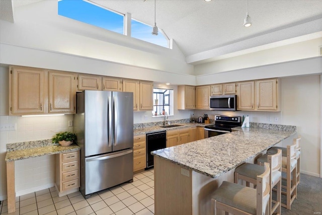 kitchen featuring appliances with stainless steel finishes, a kitchen bar, high vaulted ceiling, light brown cabinetry, and sink