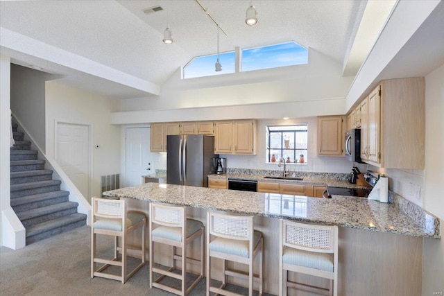 kitchen with light brown cabinets, appliances with stainless steel finishes, sink, and light colored carpet