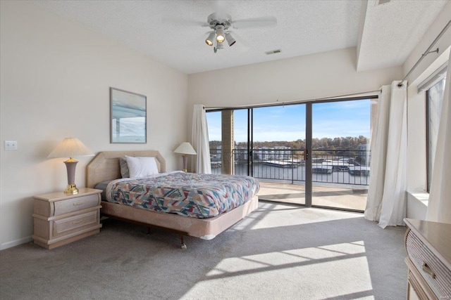 bedroom with multiple windows, light colored carpet, a water view, and ceiling fan