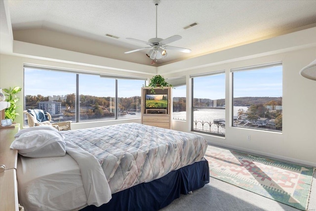 bedroom featuring carpet flooring, a water view, vaulted ceiling, a textured ceiling, and ceiling fan