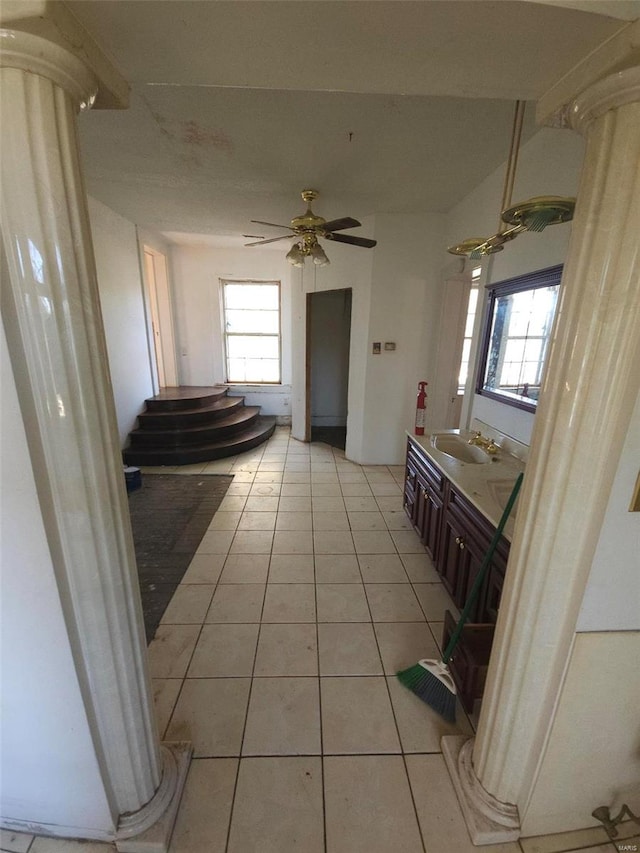 interior space with tile patterned flooring, vanity, ceiling fan, and ornate columns