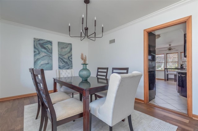 dining space with hardwood / wood-style floors, ceiling fan with notable chandelier, and ornamental molding