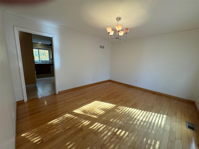 unfurnished room featuring sink, wood-type flooring, a chandelier, and crown molding