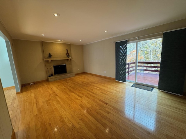 unfurnished living room featuring a fireplace, light hardwood / wood-style floors, and crown molding