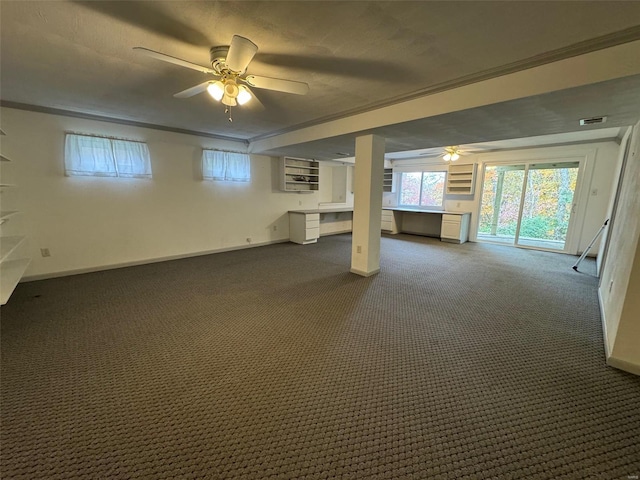 basement with ceiling fan, dark carpet, and ornamental molding