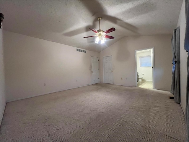 interior space with lofted ceiling, a textured ceiling, and ceiling fan