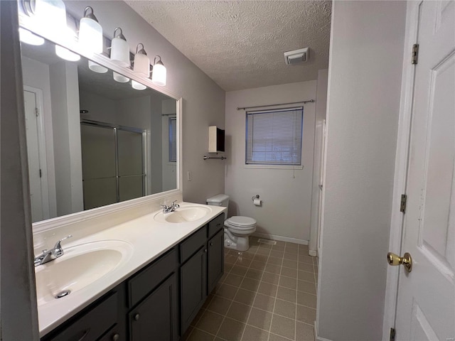 bathroom featuring toilet, vanity, a textured ceiling, and a shower with door