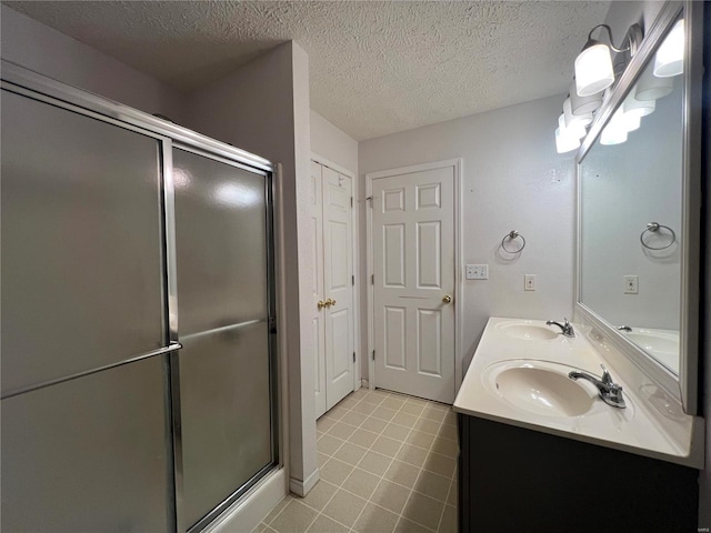 bathroom featuring vanity, a textured ceiling, and a shower with door