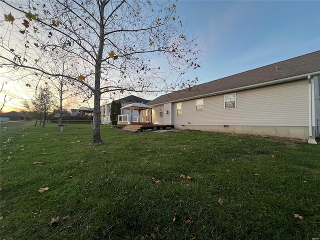 yard at dusk featuring a deck and a gazebo