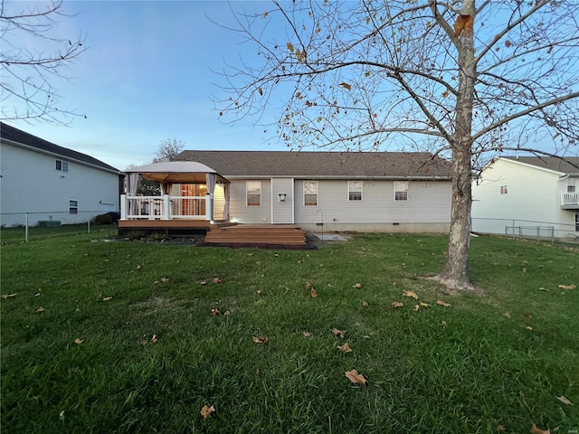 rear view of house featuring a wooden deck, a lawn, and a gazebo