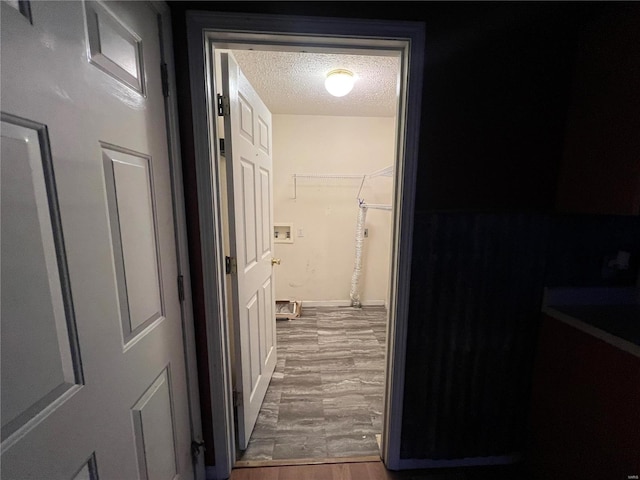 corridor with a textured ceiling and hardwood / wood-style flooring