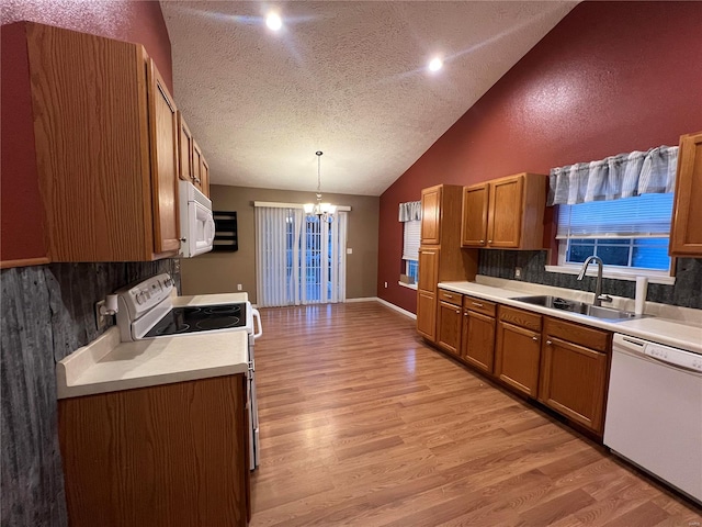 kitchen featuring sink, decorative light fixtures, white appliances, light hardwood / wood-style flooring, and lofted ceiling