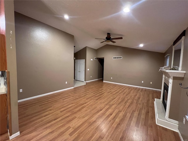 unfurnished living room with light hardwood / wood-style floors, ceiling fan, and vaulted ceiling