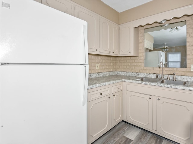 kitchen featuring white refrigerator, backsplash, light hardwood / wood-style flooring, and sink