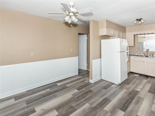 kitchen featuring white cabinetry, sink, white refrigerator, hardwood / wood-style floors, and decorative backsplash